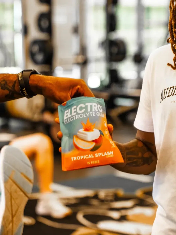 Two athletes in the gym, one handing off an Electro pouch