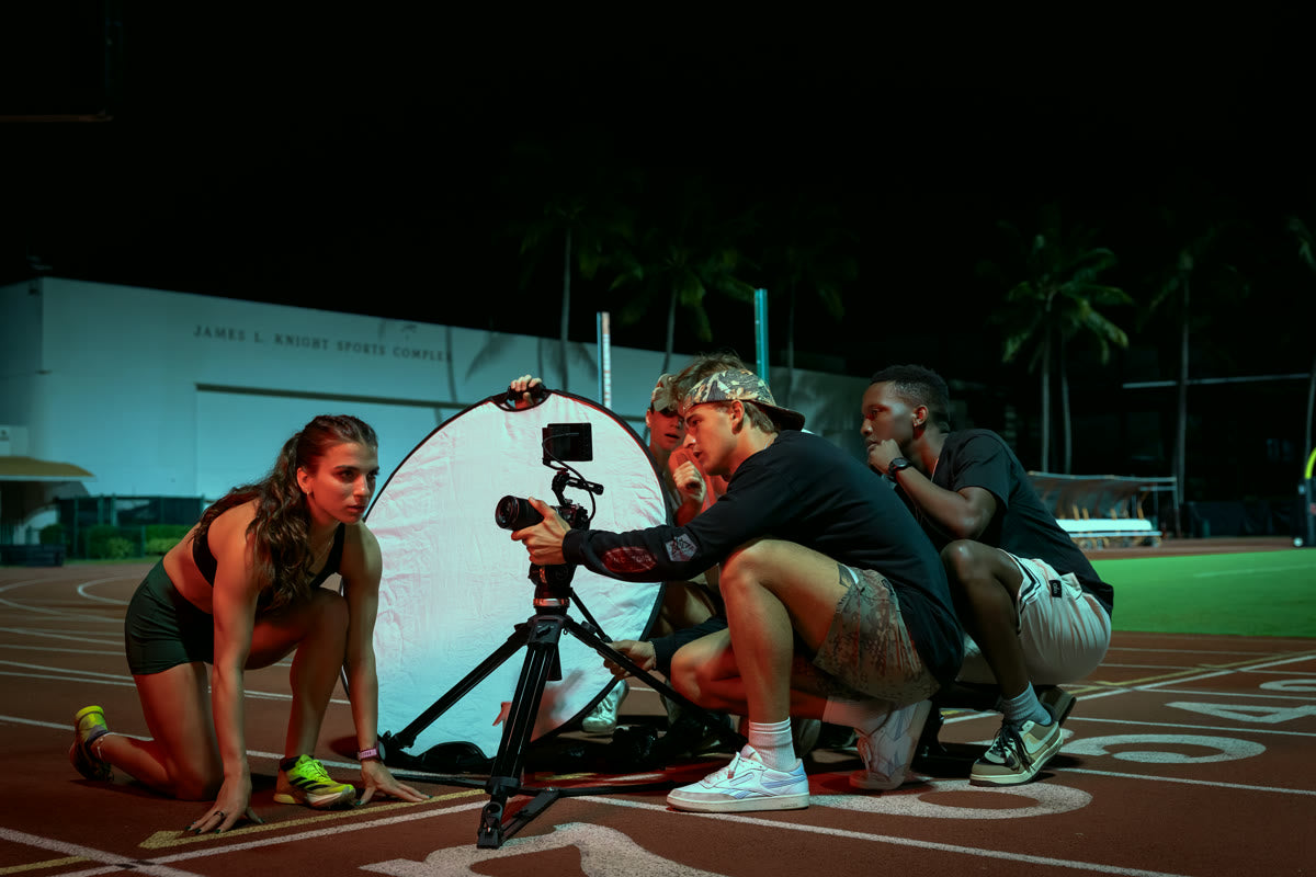Electro team filming a track athlete in starting blocks at night